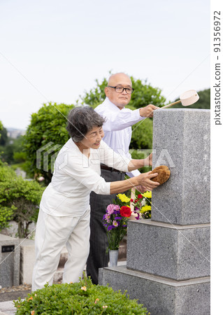 Senior couple cleaning tombstones 91356972