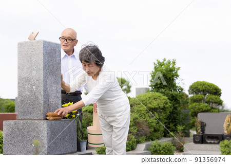 Senior couple cleaning tombstones 91356974