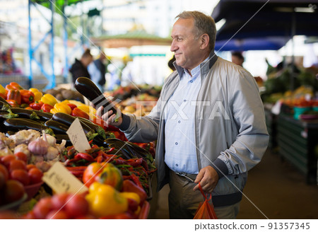 Man choosing vegetables in greengrocery Man choosing vegetables in greengrocery 91357345