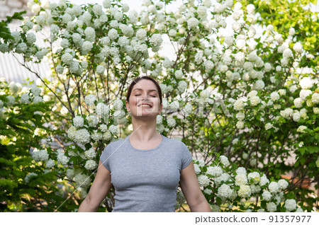 Middle-aged woman enjoying the scent of a blooming garden.  91357977