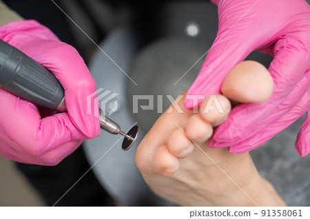 Woman on professional pedicure procedure by abrasive disc machine in beauty salon. Woman on professional pedicure procedure by abrasive disc machine in beauty salon. 91358061