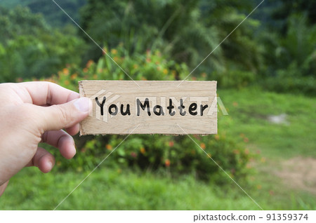 Hand holding wooden banner with text - You matter. Hand holding wooden banner with text - You matter. 91359374
