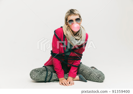 Portrait of young stylish girl in sunglasses and retro outfit posing with bubble gum isolated over grey studio background Portrait of young stylish girl in sunglasses and retro outfit posing with bubble gum isolated over grey studio background 91359400