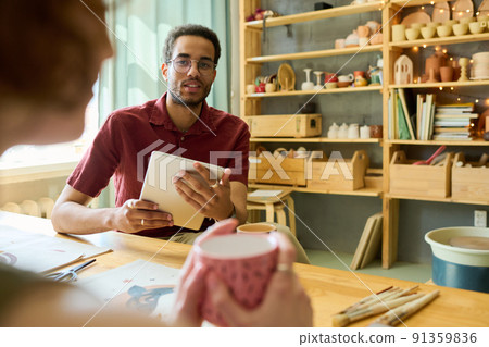 Young black man with tablet looking at female colleague during discussion 91359836
