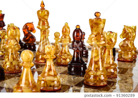 Natural amber different chess pieces figures standing on brown stone board. Close up game concept competition, Classic Gambit Tournament of confrontation. 91360289