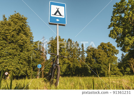 Modern sport bike leaning at camping road sign Modern sport bike leaning at camping road sign 91361231
