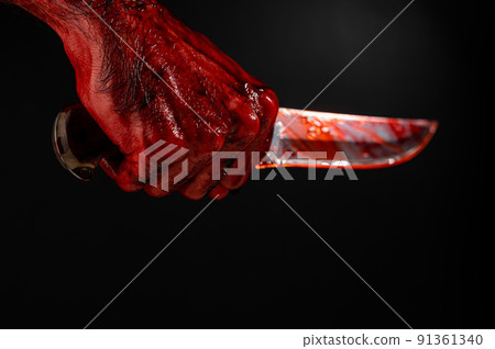 A man with bloody hands brandishes a knife on a black background. A man with bloody hands brandishes a knife on a black background. 91361340