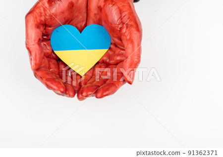 Woman with hands covered in blood holding a heart with the flag of ukraine on a white background. Woman with hands covered in blood holding a heart with the flag of ukraine on a white background. 91362371