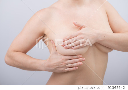 Caucasian woman self checks for breast cancer on white background.  91362642