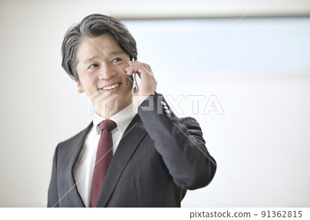 一個 50 多歲的男人在用智能手機說話 91362815