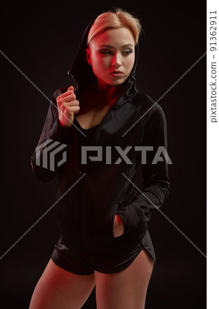 Beautiful seductive sporty girl with the slim sexy figure in the black hoodie, sport underwear and little black shorts is posing in the studio Beautiful seductive sporty girl with the slim sexy figure in the black hoodie, sport underwear and little black shorts is posing in the studio 91362911