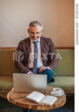 Man sitting smiling at laptop screen 91365180