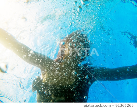 Woman floating in blue transparent bubble water. Summer sea vacation. Blurred image Woman floating in blue transparent bubble water. Summer sea vacation. Blurred image 91365263