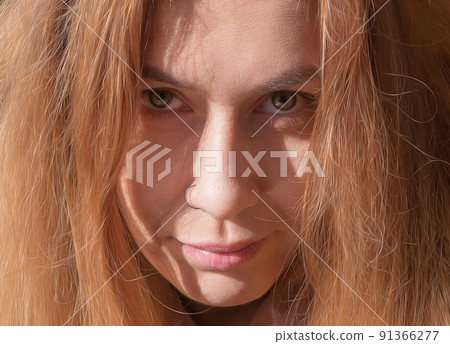 Portrait of a fair-haired woman with serious facial expressions. Closeup photo in full screen 91366277