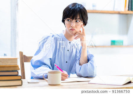 A young woman wearing dissatisfied glasses while studying in the living room A young woman wearing dissatisfied glasses while studying in the living room 91366750