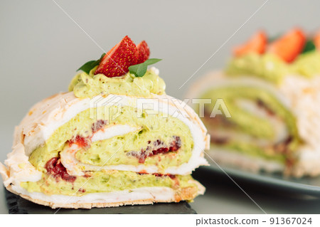 Piece of meringue roll with strawberries on a blue plate 91367024