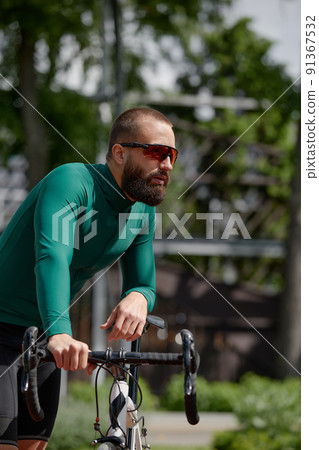 Man on bicycle rides through summer park on sunny day. 91367532