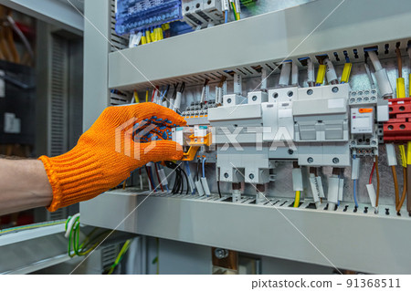 Hand of man electrical engineer mounts power energy shields close up photo 91368511