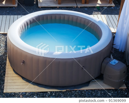 Inflatable brown and white swimming pool with turquoise water outdoors in the summer sun at the beach recreation area Inflatable brown and white swimming pool with turquoise water outdoors in the summer sun at the beach recreation area 91369099
