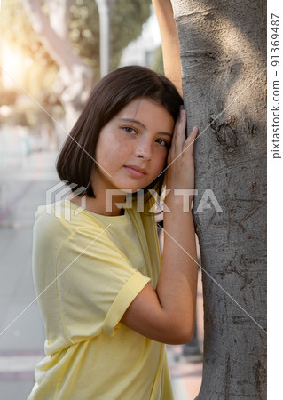 A pretty young girl leaned against a tree. A pretty young girl leaned against a tree. 91369487