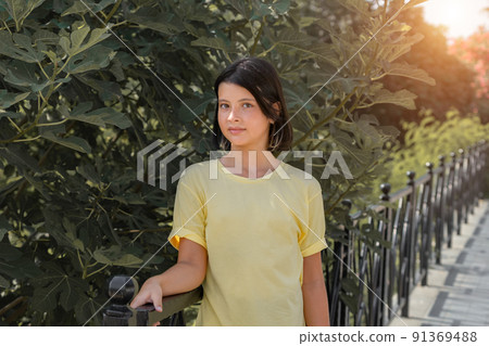 Portrait of a young girl standing near a metal fence. Portrait of a young girl standing near a metal fence. 91369488