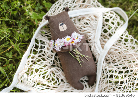 Eco-friendly cute handmade toy bear on grass at sunny summer day. 91369540