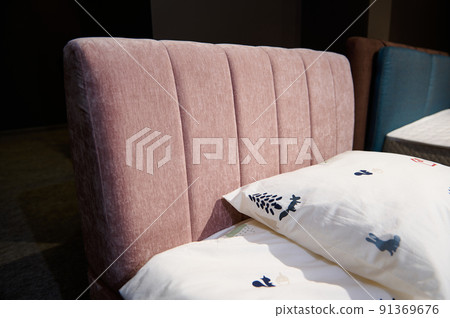 Partial view of single bed for girl upholstered in pink velour fabric displayed for sale in a furniture showroom. Home interior design concept 91369676