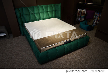 Sleeping bed made of emerald green velour upholstery with orthopedic mattress displayed for sale in furniture store. Bedroom and home interior design Sleeping bed made of emerald green velour upholstery with orthopedic mattress displayed for sale in furniture store. Bedroom and home interior design 91369706