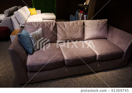Stylish, modern, minimalist and comfortable sofa with pillows displayed for sale in a home design studio and furniture store 91369745