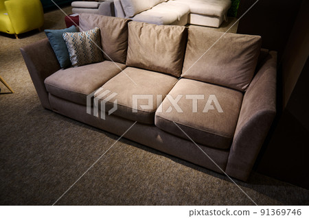 Stylish, modern, minimalist and comfortable sofa with cushions displayed for sale in a home design studio and furniture store. Overhead view 91369746