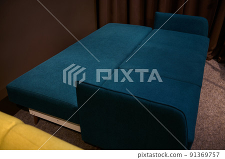 Stylish dark blue and green sofa in a folding form, on display in a furniture store. Home interior design concept Stylish dark blue and green sofa in a folding form, on display in a furniture store. Home interior design concept 91369757
