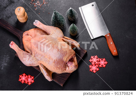 Raw turkey or chicken with salt, spices and herbs on a wooden cutting board. Preparing a christmas table Raw turkey or chicken with salt, spices and herbs on a wooden cutting board. Preparing a christmas table 91370824