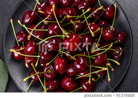 Fresh sweet cherries plate with leaves in water drops on stone background, top view Fresh sweet cherries plate with leaves in water drops on stone background, top view 91370880
