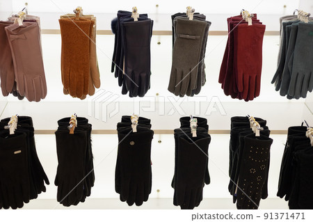 Women's gloves made of different materials and different colors hang on a showcase in a store Women's gloves made of different materials and different colors hang on a showcase in a store 91371471