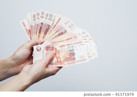 Women's hands hold five thousand ruble bills folded in a fan on a white background 91371979