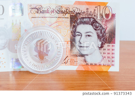 1 Australian dollar, 1oz silver coin with portrait of Queen Elizabeth II and 10 GBP Pound sterling banknote with portrait of Queen Elizabeth II. 1 Australian dollar, 1oz silver coin with portrait of Queen Elizabeth II and 10 GBP Pound sterling banknote with portrait of Queen Elizabeth II. 91373343