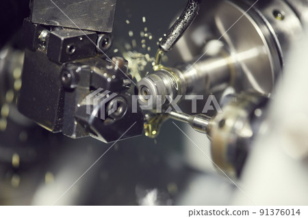 Close-up of cutting fluid pouring on drill tool of lathe machine during processing detail Close-up of cutting fluid pouring on drill tool of lathe machine during processing detail 91376014