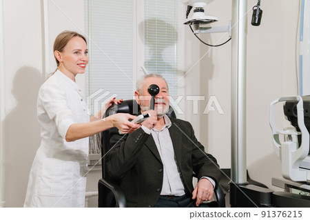 ophthalmologist diagnoses elderly man's vision on a sign projector. ophthalmologist diagnoses elderly man's vision on a sign projector. 91376215