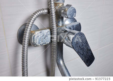 A thin stream of hard water flows from an old tap aerator. Old Bathroom Sink Faucet contaminated with calcium and grime. 91377223