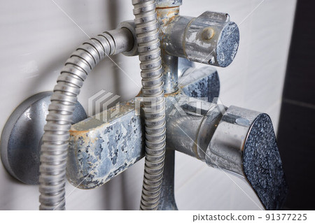 A thin stream of hard water flows from an old tap aerator. Old Bathroom Sink Faucet contaminated with calcium and grime. 91377225