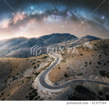 Milky Way arch and winding mountain road at night Milky Way arch and winding mountain road at night 91377384