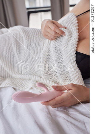 desire concept : Woman lying in bed holding a dildo vibrator in her hand to help herself. 91378297