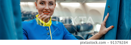 Joyful woman stewardess standing in passenger aircraft cabin 91379284