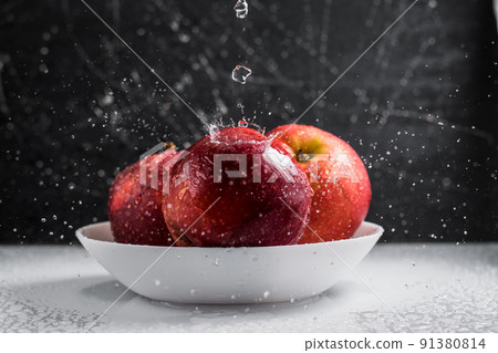Red apples in a plate of water drops. 91380814