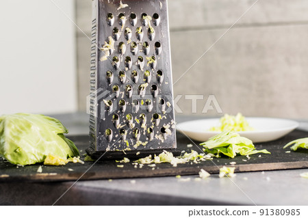 The composition of the grated cabbage. Nearby is grater and cabbage. The composition of the grated cabbage. Nearby is grater and cabbage. 91380985