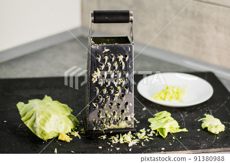 The composition of the grated cabbage. Nearby is grater and cabbage. The composition of the grated cabbage. Nearby is grater and cabbage. 91380988