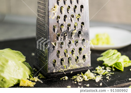 The composition of the grated cabbage. Nearby is grater and cabbage. The composition of the grated cabbage. Nearby is grater and cabbage. 91380992
