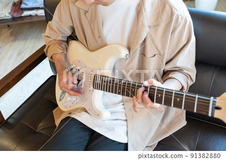 Young man playing white electric guitar Young man playing white electric guitar 91382880