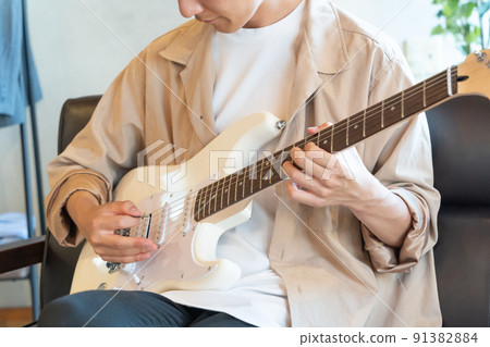 Young man playing white electric guitar 91382884