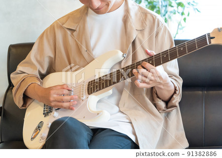 Young man playing white electric guitar 91382886